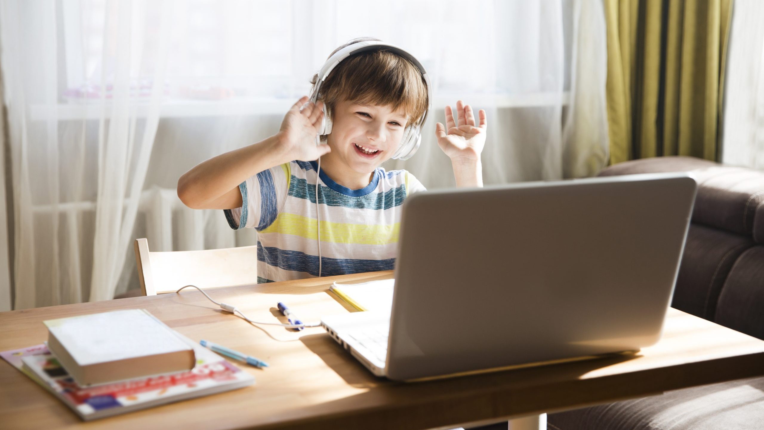 child boy in headphones is using a laptop and study online with