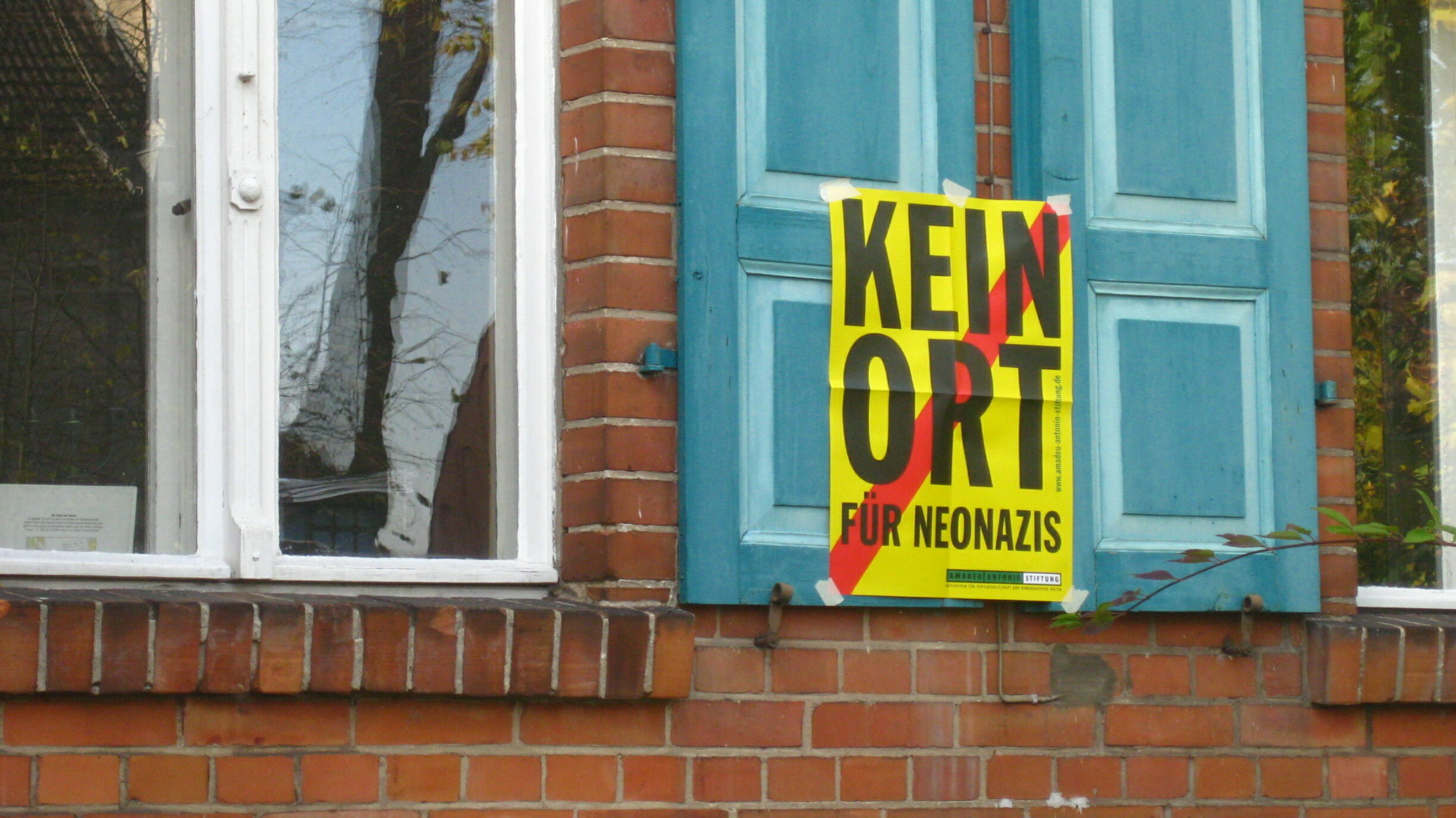 Hauswand mit "Kein Ort für Neonazis"-Plakat.